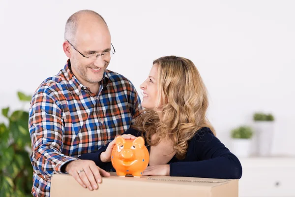 Man en vrouw met een karton en piggy bank — Stockfoto