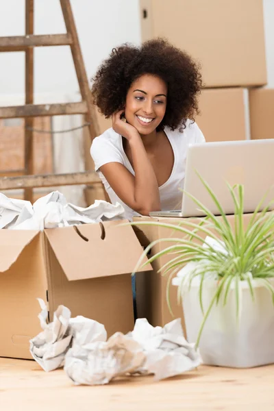 Woman checking her laptop on a cardboard box — Stock Photo, Image