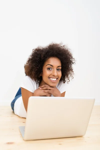 Mulher feliz deitada no chão com um laptop — Fotografia de Stock