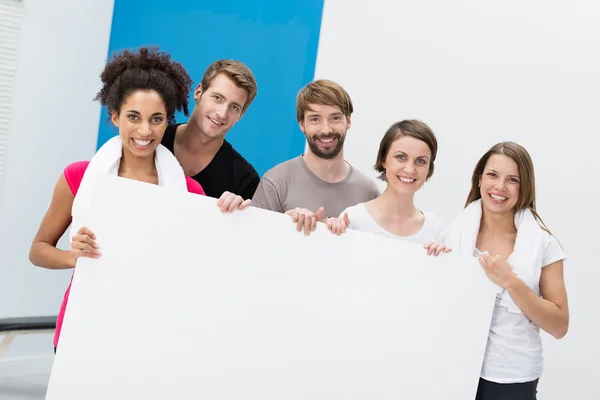 Grupo de fitness no ginásio segurando um cartão em branco — Fotografia de Stock