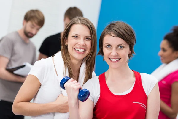 Young woman lifting weights aided by a friend — Stock Photo, Image