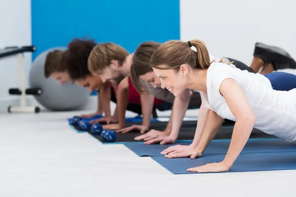 Diversos jóvenes haciendo ejercicio en un gimnasio —  Fotos de Stock