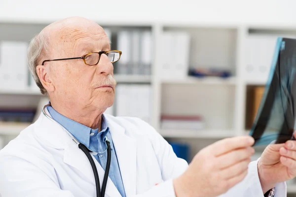 Senior male radiologist checking an x-ray — Stock Photo, Image