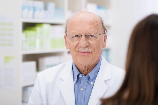 Elderly pharmacist serving a patient — Stock Photo, Image
