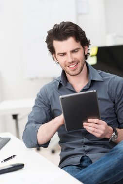 Happy businessman reading his tablet screen clipart