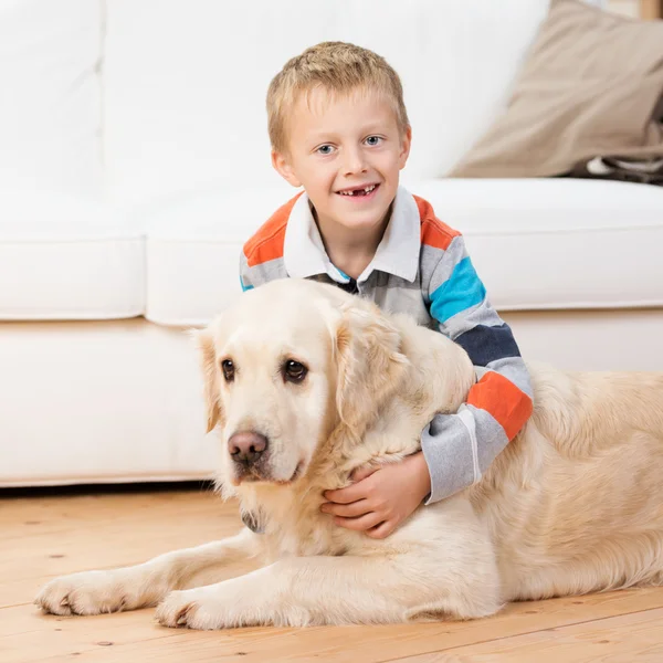 Smiling little boy playing with a golden retriever — Stock Photo, Image