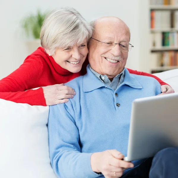 Casal de idosos divertidos usando um computador portátil — Fotografia de Stock