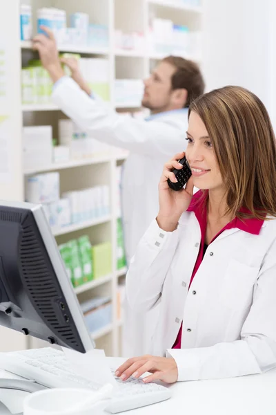 Pretty young pharmacist chatting on the phone — Stock Photo, Image