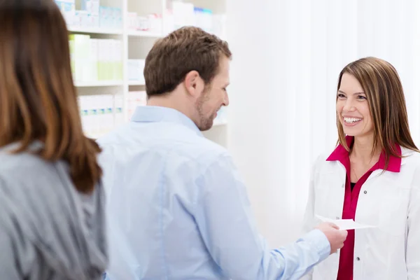 Farmacêutico sorridente amigável ajudando um cliente — Fotografia de Stock