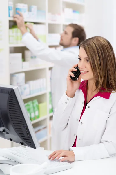 Mooie jonge apotheker chatten op de telefoon — Stockfoto