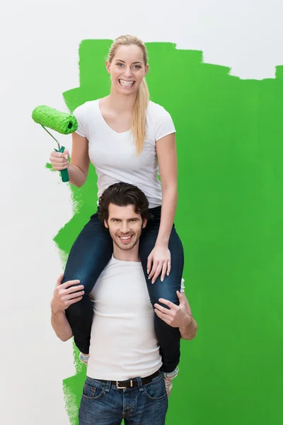 Woman getting a piggy back as she paints — Stock Photo, Image