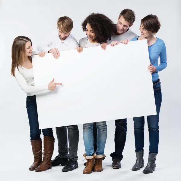 Group of young friends looking at a blank sign — Stock Photo, Image