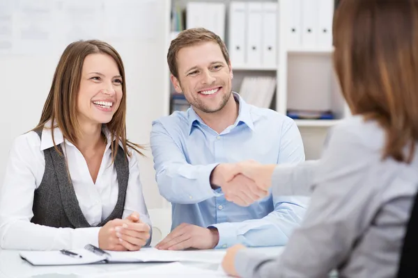 Smiling young man shaking hands with an agent — Stock Photo, Image