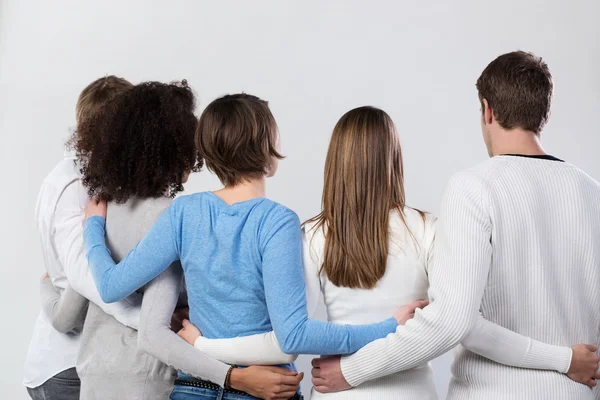 Vista trasera de un grupo de amigos brazo en brazo — Foto de Stock