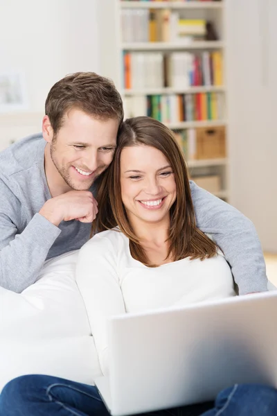 Pareja joven sonriendo al contenido en el portátil — Foto de Stock