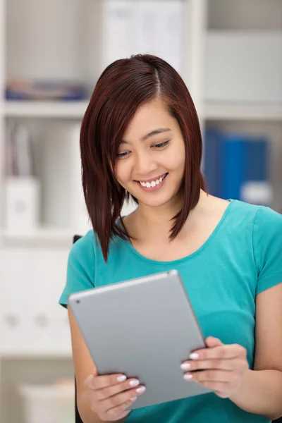 Junge asiatische Frau lächelt, während sie ihr Tablet liest — Stockfoto