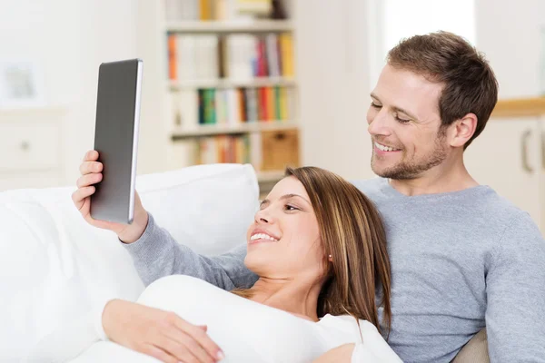 Casal jovem compartilhando um computador tablet — Fotografia de Stock