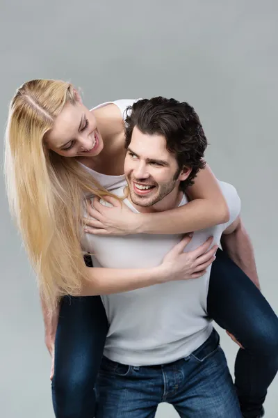 Playful couple riding piggy back together — Stock Photo, Image