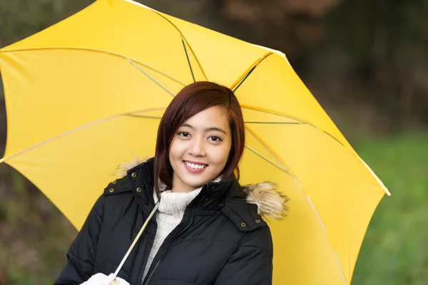 Attractive smiling woman under a yellow umbrella — Stock Photo, Image