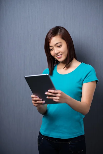 Mujer sonriendo mientras lee una tableta — Foto de Stock