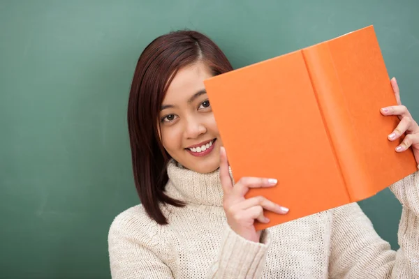 Student "peering" rond haar leerboek — Stockfoto