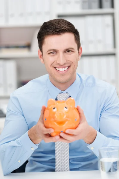 Empresário sorridente segurando um banco porquinho — Fotografia de Stock