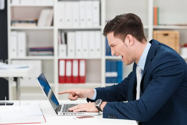 Uomo d'affari urla e indica il suo computer portatile — Foto Stock