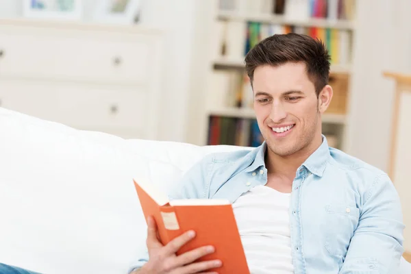 Sonriente hombre relajante disfrutando de un libro — Foto de Stock
