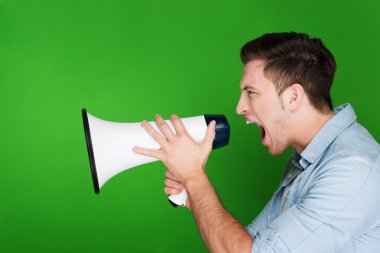 Angry young man yelling into a megaphone clipart