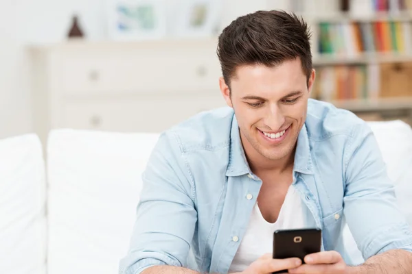 Hombre sonriendo anuncio que lee un mensaje en su móvil —  Fotos de Stock