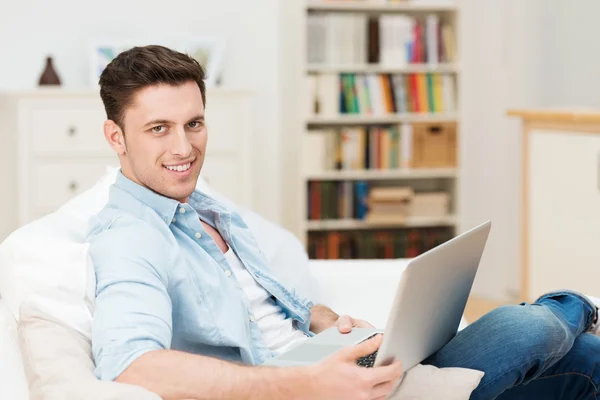 Jeune homme relaxant à la maison avec un ordinateur portable — Photo