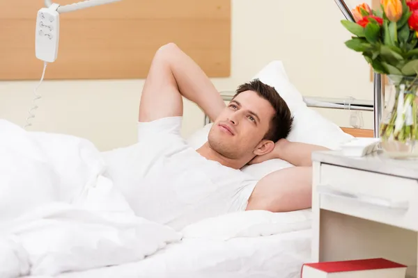 Junger Mann liegt tagträumend im Bett — Stockfoto
