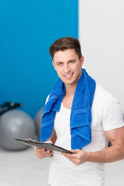 Jeune homme debout dans une salle de gym avec un presse-papiers — Photo