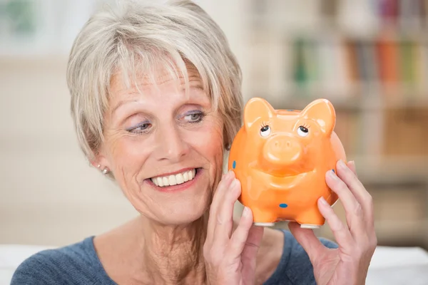 Charismatic elderly woman holding up a piggy bank — Stock Photo, Image
