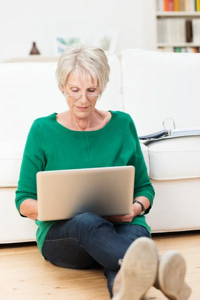 Senior woman relaxing at home with a laptop — Stock Photo, Image