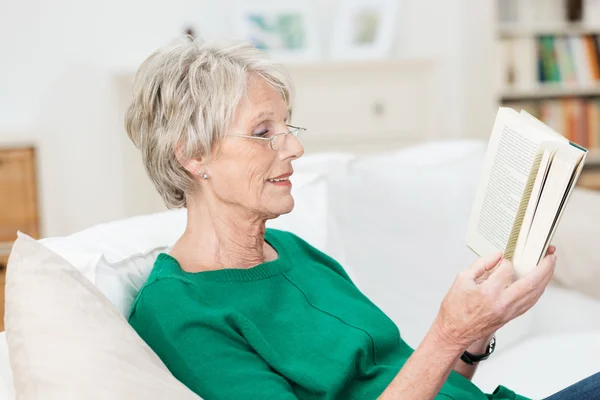 Приваблива літня жінка читає вдома — стокове фото