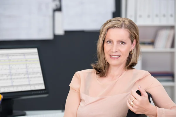 Middle-aged businesswoman sitting at her desk — Stock Photo, Image