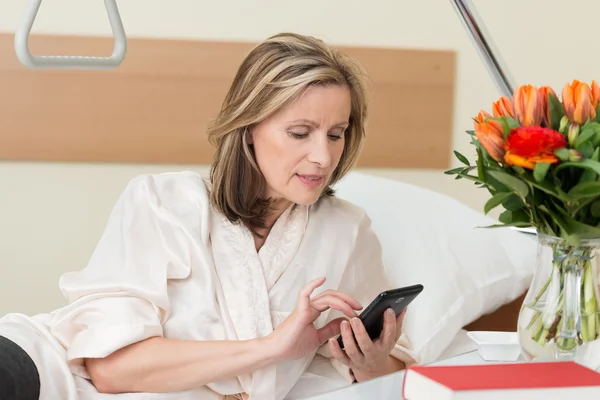 Woman sending a text message in hospital — Stock Photo, Image