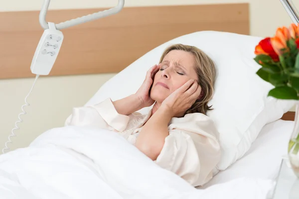 Mulher com dor em uma cama de hospital — Fotografia de Stock