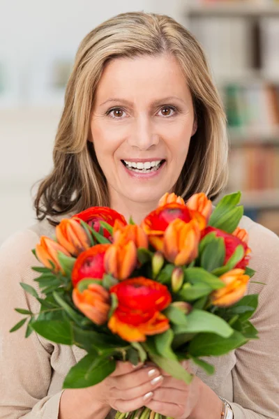 Happy smiling woman with a gift of flowers — Stock Photo, Image