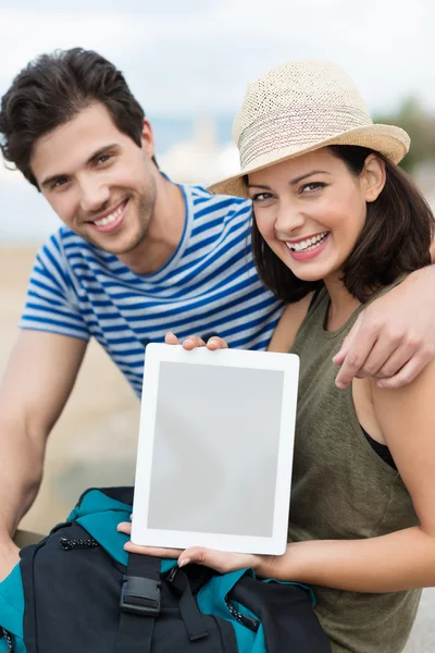 Couple at beach displaying tablet