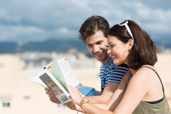 Pareja buscando en folletos turísticos — Foto de Stock