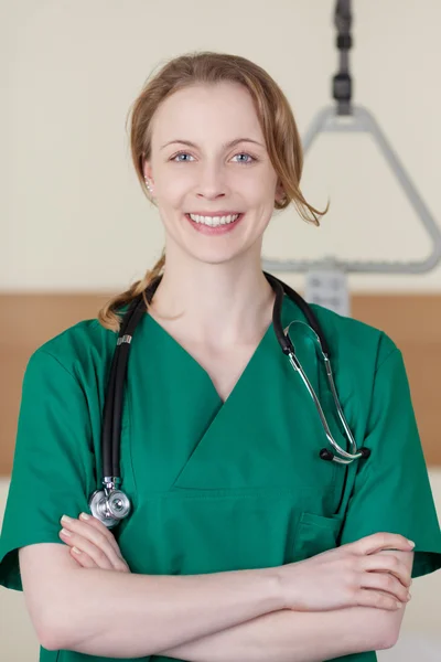 Lachende jonge vrouwelijke arts in scrubs — Stockfoto