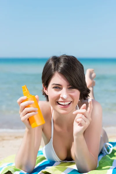 Morena aplicando protetor solar na praia — Fotografia de Stock