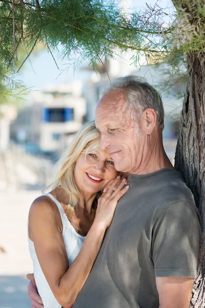 Pareja madura acurrucándose bajo el árbol — Foto de Stock