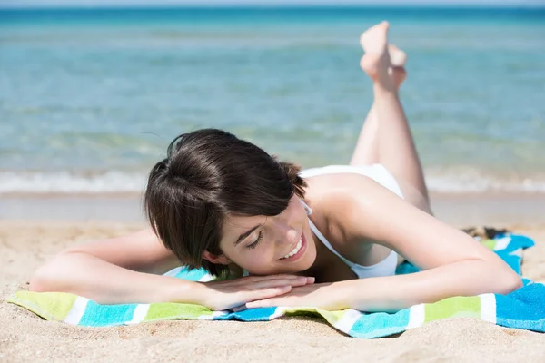 Νεαρή γυναίκα κάνει ηλιοθεραπεία στην παραλία — Φωτογραφία Αρχείου