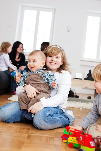 Girl with baby sitting on floor — Stock Photo, Image