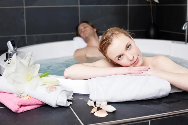 Mujer relajándose con el hombre en el jacuzzi — Foto de Stock