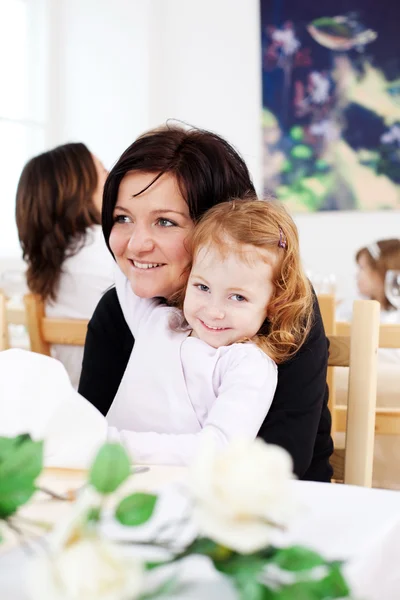 Flicka sitter med mamma i restaurang — Stockfoto