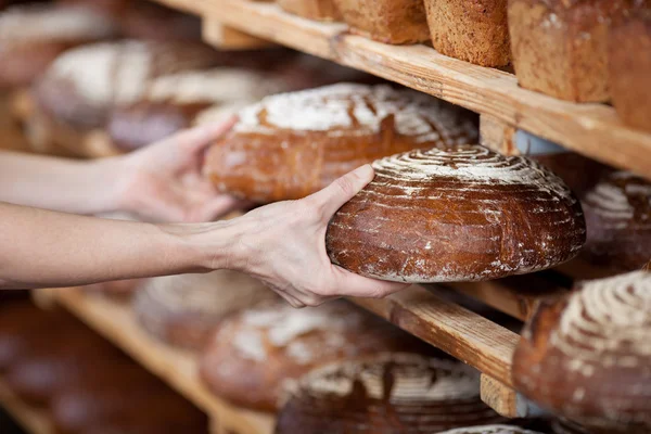 De verkoopster handen verwijderen brood uit rekken — Stockfoto